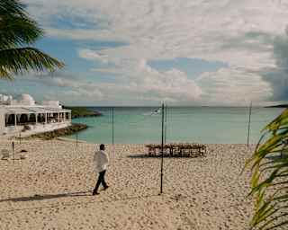 A male staff member walks across the beach by Cip's restaurant to a waterfront celebration table laid for twelve guests.