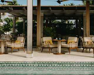 Three sets of tables and lounge chairs enjoy The Jungle Area outdoor terrace at Uchu, with a backdrop of ferns and palms.