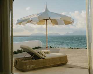 A luxurious sun lounger reclines beneath a pointed parasol on the pool terrace of the Spa by Guerlain, overlooking the bay.