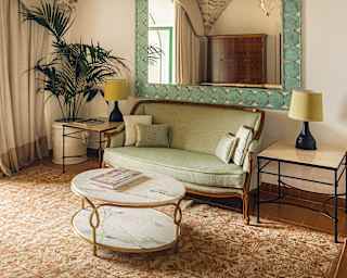 A classic Neapolitan sofa with wooden frame and pale green upholstery is flanked by lime shaded table lamps and large plant