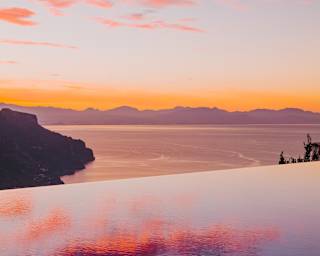 Reflections of fuchsia cotton candy clouds float effortlessly on an infinity pool as it fades into the purple horizon