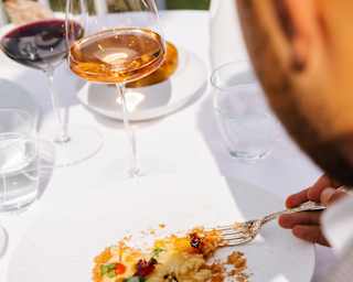 A diner enjoys Belvedere's Risotto Caprese, with mozzarella, tomatoes and basil, served with wine at a sunny al-fresco table.