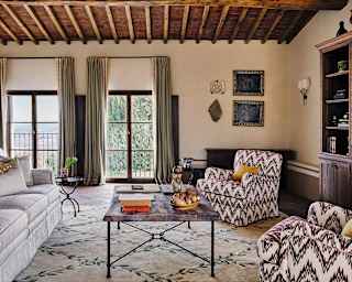 The lounge exudes elegance and peace, with a sofa and chairs in simple tones, neutral décor and windows with verdant views.