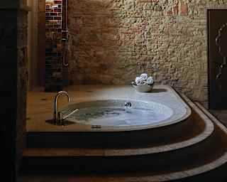 Circular hot tub in a rustic, underground, stone-walled spa