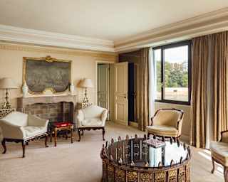 A glass-topped coffee table with Moorish decoration takes centre spot in a large sitting room with ivory antique furnishings