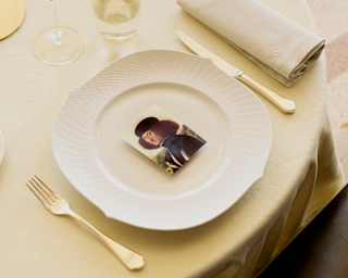 A card with a self-portrait by the Italian painter Vittore Carpaccio rests in the centre of a plate, with cutlery either side.