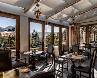 Curiña's dining tables and chairs enjoy shade below a canopied glass roof and wonderful views through wide window walls.