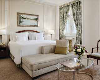 An inviting smoke grey velvet chaise longue sits at the foot of a king bed topped with impossibly crisp white linens