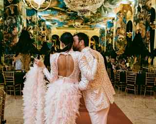 Shot from behind of a newly married couple in sharing a kiss in a glamorous room