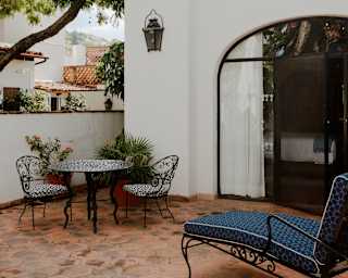 A blue lounge chair and a filigree table with two seats offer relaxation on the terrace of Junior Suite at Casa Principal.