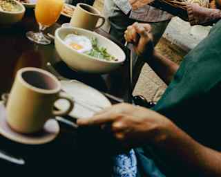Angled image of Andanza guests breakfasting on coffee, juice and eggs, attended by a waitress carrying a basket of pastries.