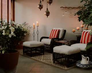 Two wicker chairs with foot stools await guests at the spa, serene with natural décor, candles, pendant lights and plants.