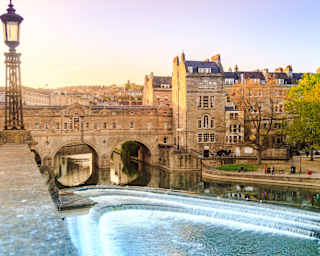 View across a river of Bath city with a stone bridge and a row of Georgian houses