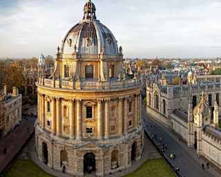 View from above of Oxford's Radcliffe Camera Library and All Souls College, as the yellow-tinted stone glows in evening sun.