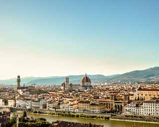 View over the river Arno to Florence's cathedral duomo, spires and belltowers which rise from a cluster of terracotta roofs.