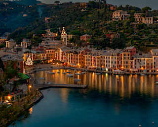 Portofino marina on a Christmas night, lined with glittering waterside restaurants casting reflections on the dark water.