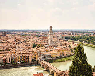View of Ponte Pietra bridge crossing the Adige River to Verona's centre where the Torre dei Lamberti rises above tiled rooftops.