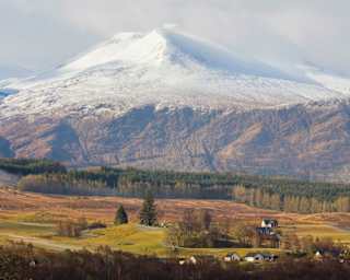 The mountain of Aonach Mor, linked by a mountain pass to Aonach Beag, rises from the glen, gathering snow as it ascends.
