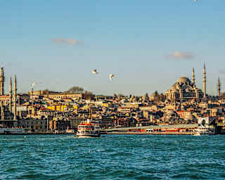 View across the choppy Bosphorus Strait, where a ferry chugs towards Istanbul's rooftops, minarets and Suleymaniye Mosque.