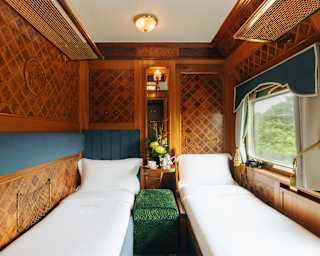 Twin beds divided by a green seat and side table, cocooned in polished marquetry, showcases the cabin's day and night luxury.