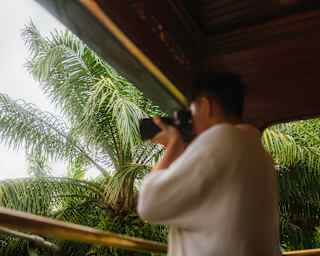 In a low-angle soft-focus shot, a man in a white shirt points a long-lens camera at the view from the Observation Deck.