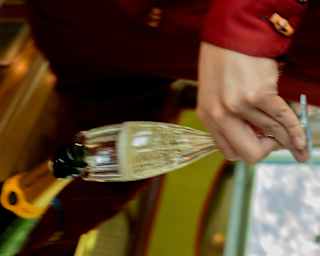 Looking down on a waiter's hands as he fills a flute with Veuve Clicquot Champagne, seen at an angle in soft-focus.