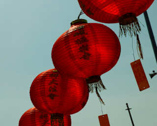 View up of tags, inscribed with wishes, dangling from red, paper lanterns, hung in a row outside the Goddess of Mercy Temple.