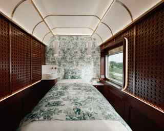 View into a panelled Dior Spa room with a teal and white Toile De Jouy feature wall and treatment bed with matching covers.