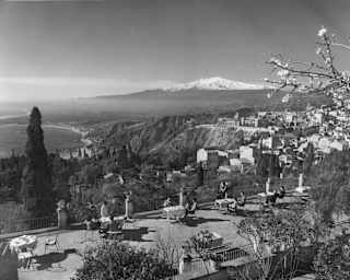 Black and white image of the terrace with views of Taormina's town and coastline, and the breathtaking, snowy-capped Etna.