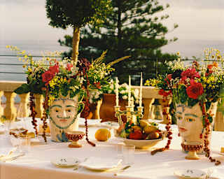 Extravagant flower arrangements in two traditional Sicilian moor's head ceramic vases adorn a sea-view celebration table.