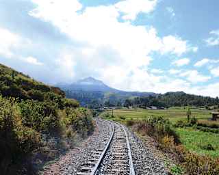 Train tracks winding along a valley towards a Peruvian mountain top