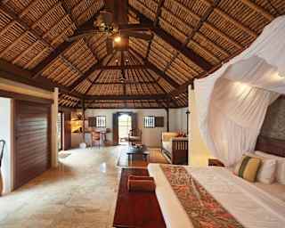 Vast bedroom with a pillowy king-bed under a linen canopy in a double-height villa