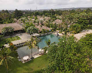 Birdseye view of the aquamarine pool, set in Jimabaran Puri's calming gardens surrounded by traditional thatch accommodation.