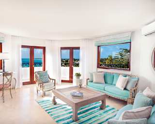 This charming living room offers views of the bay from four angles. Cool marble floors are softened by a turquoise rug