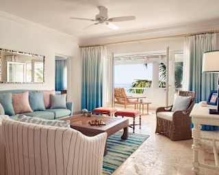 Spacious living-room with pastel hued soft furnishings and wooden coffee table
