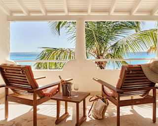 Two deck-chairs facing overlooking palm trees and the Caribbean sea