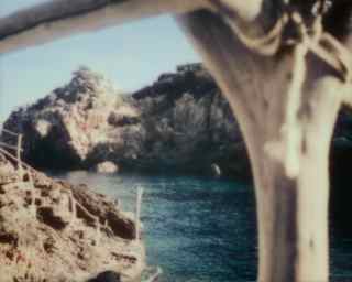 Bleached driftwood is tied together to make railings down to a secret cove where limestone cliffs meet a cobalt dark sea