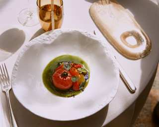 A vibrant vegan appetizer comprises a local Ramallet tomato in green tomato juice with grilled strawberries and black olive.