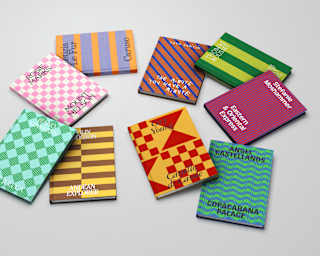 Nine books lie scattered on a surface, with geometrically patterned two-tone covers and titles pertaining to Belmond hotels.