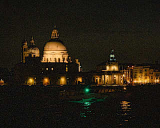 The Basilica Santa Maria and the Doge's palace create a parade of grand, warm-lit edifices, seen from the canal at night.