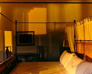 Sunlight plays in shades of honey and gold on the walls and four-poster bed of suite in a Palacio Nazarenas.