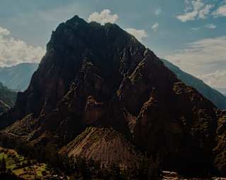 View of a rock mountain bearing down over the agricultural land by the village of Ollantaytambo in the Sacred Valley.