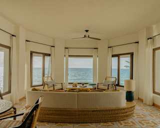 A sofa area claims extraordinary sea views through five windows on all sides of Villa Xuxú's living room, seen from behind.