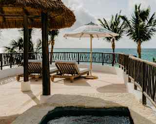 A wood rail surrounds Villa Xuxú's terrace which has a pool, thatched shade and lounge-chairs facing a blissful sea view.