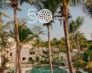 A luxurious hotel pool surrounded by palm trees, loungers, and lush greenery. The image has a 50 Best Hotels 2024 logo in the top centre.