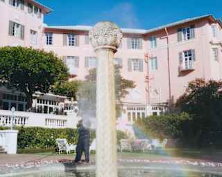A rainbow dances in spray falling from the top of the ornate stone pillar water feature in Mount Nelson Hotel's fountain.