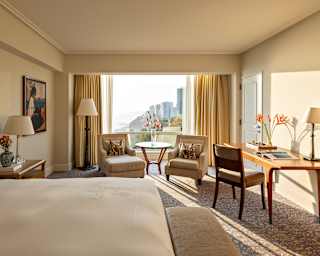 View of the Club Deluxe Junior Suite from the bed, looking over a desk, two armchairs and a huge window on to Lima's coast.