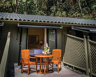 Two chairs and a matching wooden circular table on a sunny patio