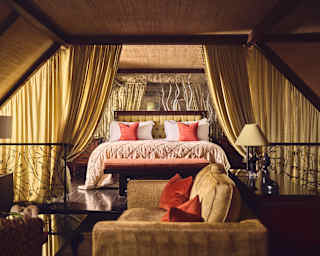 A bed with a peach quilt, sunset silk cushions and gold drapes brings a taste of Asia to the Jade 'Les Jardins' Suite.