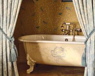 View through tied-back French country-style drapes into Hyacinth's gold-papered bathroom with hand-painted Victorian bathtub.